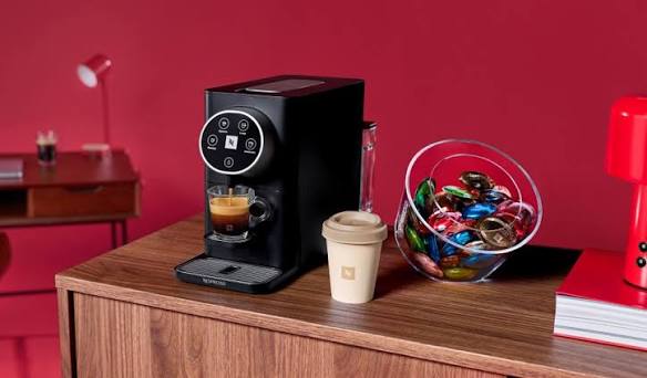 Machine noire sur un bureau, avec un bol de capsules